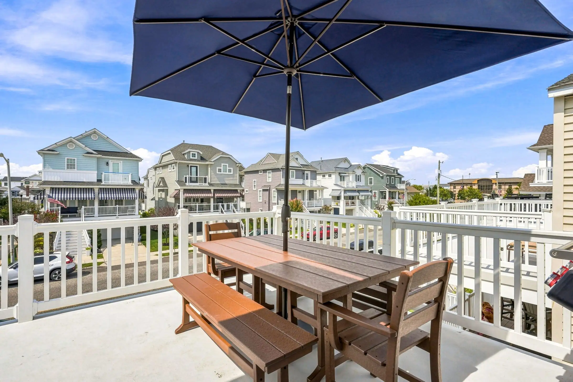 Top-floor deck with a dining table for eight under a navy umbrella