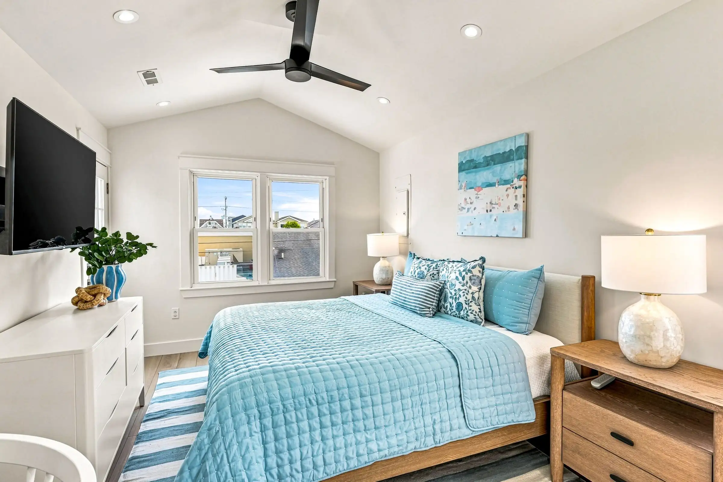 Primary bedroom with a king bed, ceiling fan, and wall-mounted TV
